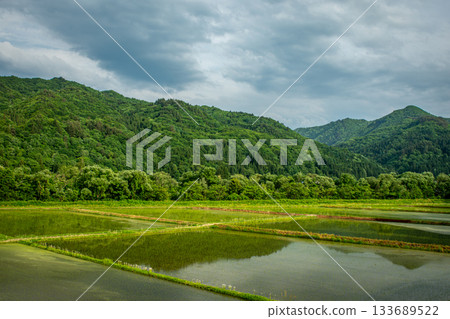 Early summer in Minamiaizu town: a landscape of lush green mountains and expansive rice paddies Early summer in Minamiaizu town: a landscape of lush green mountains and expansive rice paddies 133689522