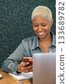 African American woman with short blond hair is sitting at desk with laptop in front of her.  133689782