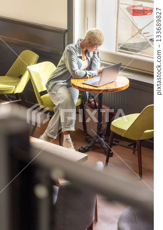 African American woman with white hair sits at desk with laptop, is surfing the Internet. female blogger. 133689827