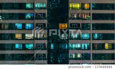window of the multi-storey building of glass and steel lighting and people within timelapse 133689988