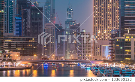 Evening Dubai marina city centre with floating vessels day to night timelapse 133690123
