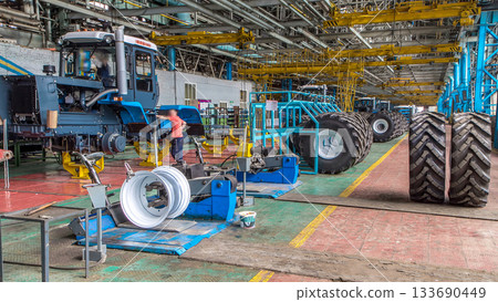 Professional mechanic install tire on wheel in repair service on tractor factory timelapse. Professional mechanic install tire on wheel in repair service on tractor factory timelapse. 133690449