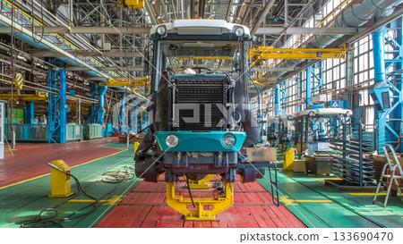 Conveyor assembly stage the body of tractor at big industrial factory timelapse Conveyor assembly stage the body of tractor at big industrial factory timelapse 133690470