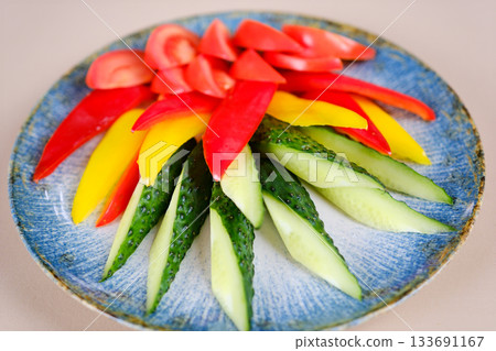 Colorful sliced vegetables of courgette and tomato on the plate on the white background 133691167