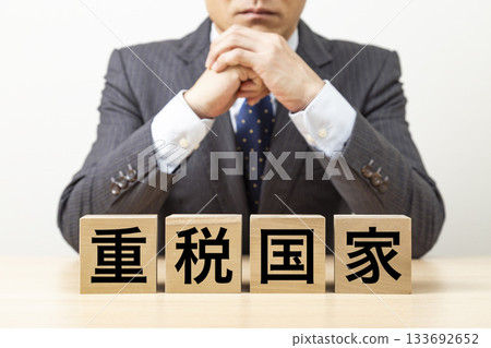 A block with the word "heavy taxation nation" written on it and a businessman 133692652