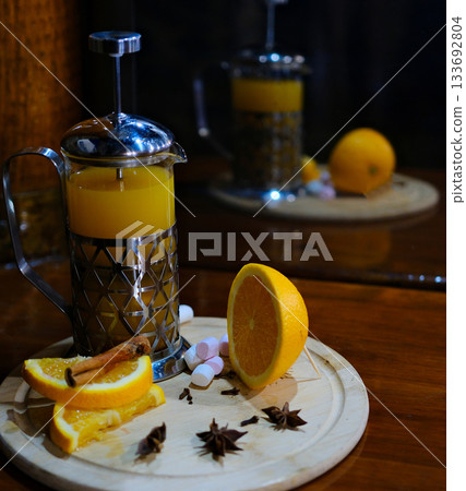pour hot sea buckthorn tea into a glass teapot Waiter pouring healthy sea buckthorn tea from glass teapot into white cup on wooden table in cafe 133692804