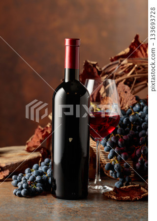 Bottle of red wine with blue grapes on a brown background. Bottle of red wine with blue grapes on a brown background. 133693728