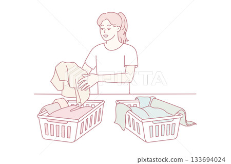 serene woman methodically arranges charitable clothing into baskets during peaceful afternoon 133694024