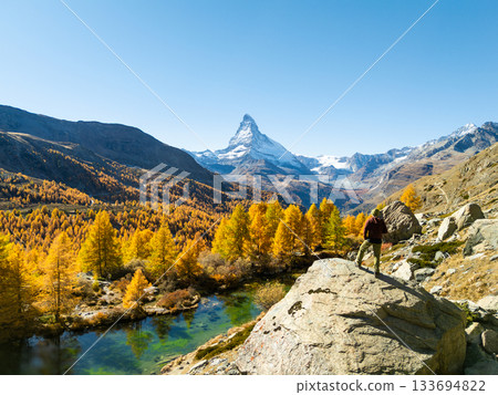 Hiker Looking at Matterhorn Mountain. Yellow Larches in Autumn. Lake Grindjisee. Zermatt Hiker Looking at Matterhorn Mountain. Yellow Larches in Autumn. Lake Grindjisee. Zermatt 133694822