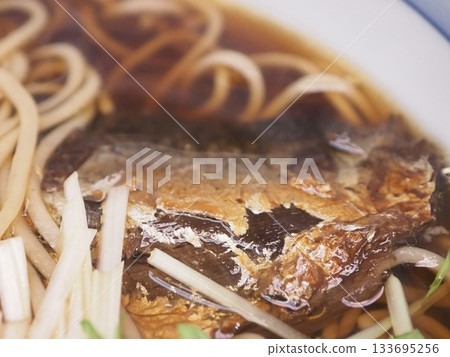 Warm herring soba noodles topped with large, sweet and spicy boiled herring fillets 133695256