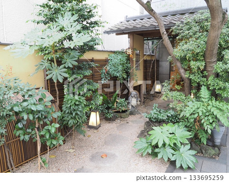 A charming Japanese restaurant garden with raccoon figurine and lit stone lanterns A charming Japanese restaurant garden with raccoon figurine and lit stone lanterns 133695259
