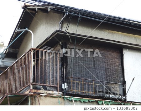 Rusty veranda and sunshade blinds of a dilapidated wooden apartment building Rusty veranda and sunshade blinds of a dilapidated wooden apartment building 133695302