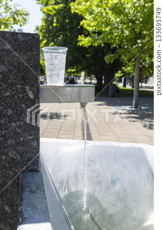 Refreshing mineral water in plastic cup at public fountain Refreshing mineral water in plastic cup at public fountain 133695749