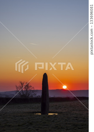 Ancient menhir standing in field during vibrant sunset 133696081