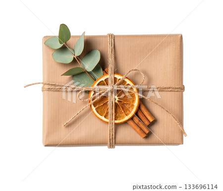 Isolated Christmas gift box wrapped in kraft paper with twine, dried orange slices, cinnamon sticks and eucalyptus. Eco holiday present concept. 133696114