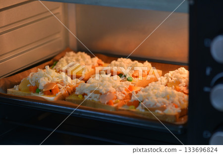 home cooking With slices of bread, topped with cheese, sausage, ham, beans and carrots, baked in an electric oven. home cooking With slices of bread, topped with cheese, sausage, ham, beans and carrots, baked in an electric oven. 133696824