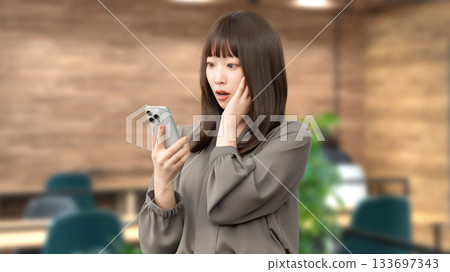 A woman/businesswoman is surprised at the screen of her smartphone 133697343