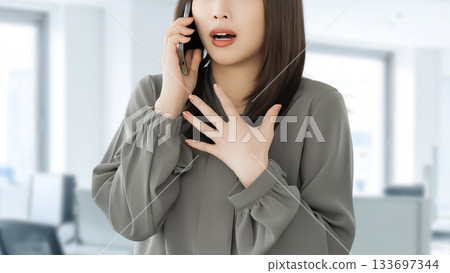 A woman/businesswoman surprised while talking on her smartphone A woman/businesswoman surprised while talking on her smartphone 133697344