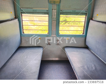 Empty seats, windows and berths inside a second class sleeper compartment in a train run by the Indian Railways. electric sockets for mobile and laptop charging Empty seats, windows and berths inside a second class sleeper compartment in a train run by the Indian Railways. electric sockets for mobile and laptop charging 133697518