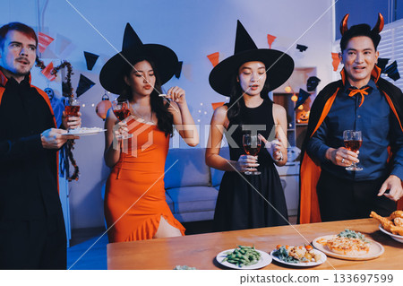 Joyful office Halloween party with coworkers in costumes, celebrating with drinks and laughter, fostering teamwork and festive spirit 133697599