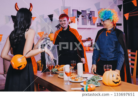 Joyful office Halloween party with coworkers in costumes, celebrating with drinks and laughter, fostering teamwork and festive spirit 133697651