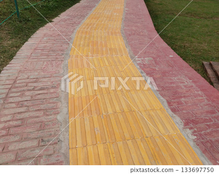 brick walkway with yellow lines for blind person. sidewalks for the disabled. tactile paving or tactile or tactile sidewalk strips for the visually impaired (blind), on pedestrians in city parks 133697750
