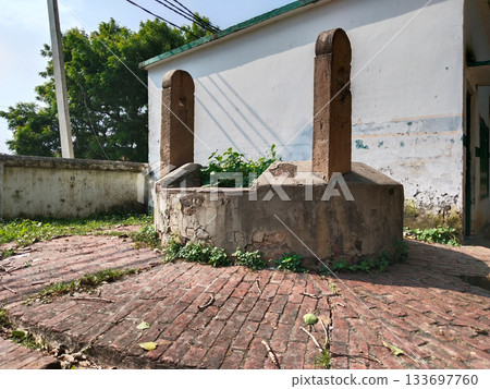 Historic, old traditional water well without water in well, everywhere Grass growing in water well 133697760