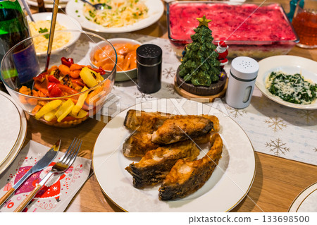 Festive table with fried carp, vegetable salad, and traditional holiday dishes 133698500
