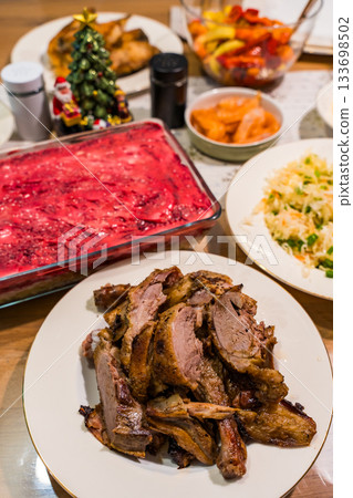 Festive table with roast duck and traditional herring under a fur coat salad Festive table with roast duck and traditional herring under a fur coat salad 133698502