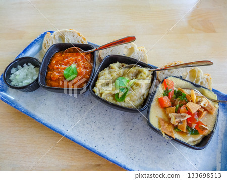 Traditional Romanian appetizer platter with zacusca, eggplant salad, hummus and fresh bread 133698513