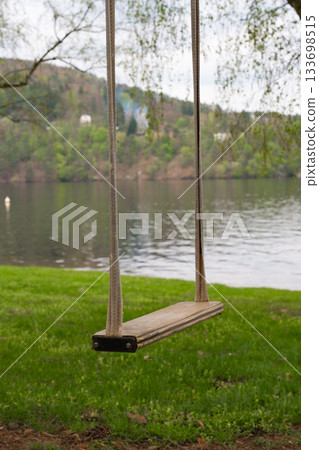 Wooden swing hanging near lake shore with forested hills in Nova Zivohost, Czech Republic Wooden swing hanging near lake shore with forested hills in Nova Zivohost, Czech Republic 133698515