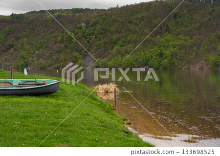 Rowboat on grassy riverbank with forest view at Nova Zivohost Rowboat on grassy riverbank with forest view at Nova Zivohost 133698525