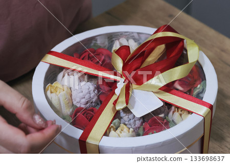 Female entrepreneur assembling marshmallow flowers in a hat box for a gift, box with homemade marshmallow tied with colorful ribbons, marshmallow tulips and roses Female entrepreneur assembling marshmallow flowers in a hat box for a gift, box with homemade marshmallow tied with colorful ribbons, marshmallow tulips and roses 133698637