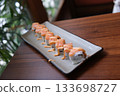 Elegant platter featuring fresh salmon nigiri arranged with artisanal sushi rolls including grilled eel drizzled with sauce, vibrant tuna and salmon cubes, mango topped rolls. 133698727