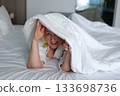 Playful cozy bed face happy woman laughing smiling rejoice flirt girl looking duvet peek toothy dental smile bedroom home pleasure tenant glad enjoying joy bed positive dentistry delight homeowner 133698736
