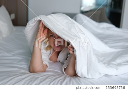 Playful cozy bed face happy woman laughing smiling rejoice flirt girl looking duvet peek toothy dental smile bedroom home pleasure tenant glad enjoying joy bed positive dentistry delight homeowner 133698736