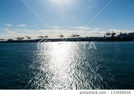 Tokyo's large cranes seen from Odaiba under the dazzling sunlight across Tokyo Bay 133698836