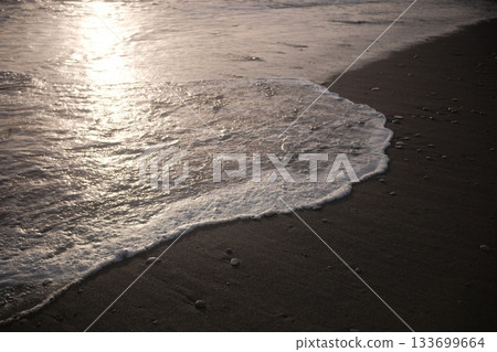 Shoreline at the beach with a setting sun, waves sand and no people Shoreline at the beach with a setting sun, waves sand and no people 133699664