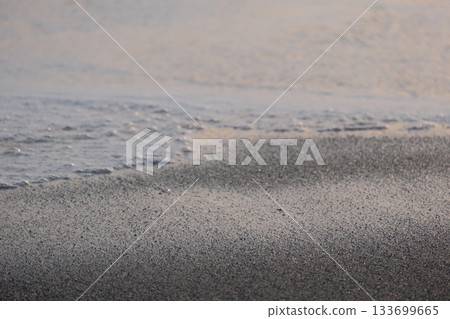 Shoreline at the beach with a setting sun, waves sand and no people Shoreline at the beach with a setting sun, waves sand and no people 133699665
