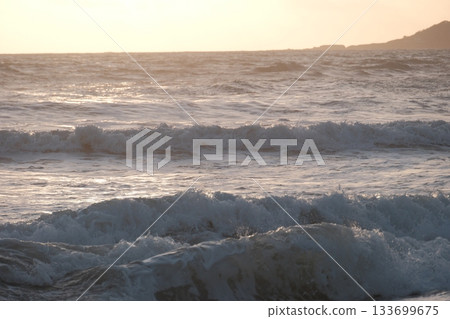 Shoreline at the beach with a setting sun, waves sand and no people Shoreline at the beach with a setting sun, waves sand and no people 133699675
