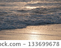 Shoreline at the beach with a setting sun, waves sand and no people 133699678