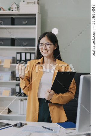 Business woman using calculator for do math finance on wooden desk in office and business working background, tax, accounting, statistics and analytic research concept. Business woman using calculator for do math finance on wooden desk in office and business working background, tax, accounting, statistics and analytic research concept. 133699848