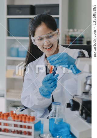 Portrait, science and happy woman on laptop in lab to research chemistry, test or innovation. Microscope, scientist and face of medical doctor in goggles for microbiology, healthcare or pharma study 133699865