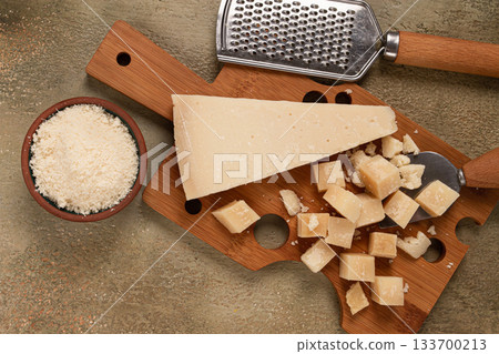 Freshly sliced and grated cheese, parmesan cheese, on a wooden chopping board, rustic style, no people 133700213