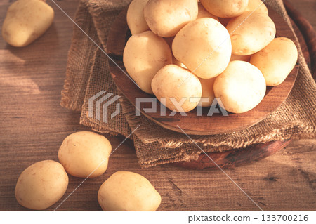 boiled new potatoes, in a wooden bowl, on a rustic table, natural light, no people, 133700216