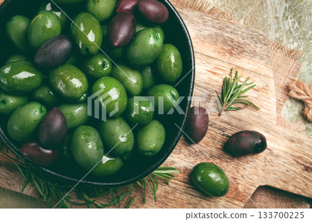 Chalkidiki olives, classic Greek green olives, in a bowl on a cutting board, top view, without people, Chalkidiki olives, classic Greek green olives, in a bowl on a cutting board, top view, without people, 133700225