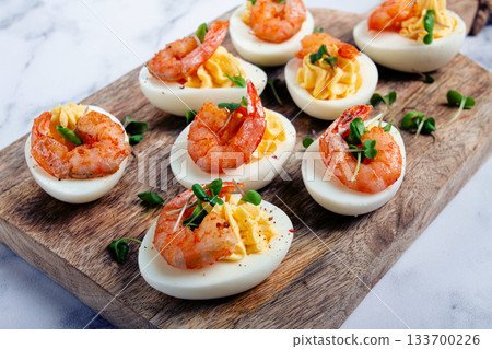 Boiled eggs stuffed with yolk and seasoned with mayonnaise, stuffed eggs with shrimp, on a wooden chopping board, selective focus, close-up, no people, Boiled eggs stuffed with yolk and seasoned with mayonnaise, stuffed eggs with shrimp, on a wooden chopping board, selective focus, close-up, no people, 133700226