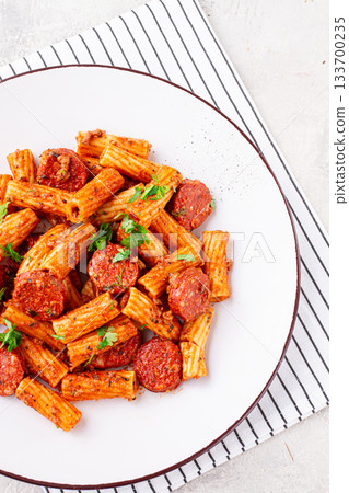 rigatoni pasta with spicy sausage, and rich tomato sauce served, on a white plate, homemade, 133700235