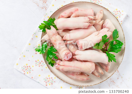 Pork trotters arranged on a plate with fresh parsley on a white background 133700240