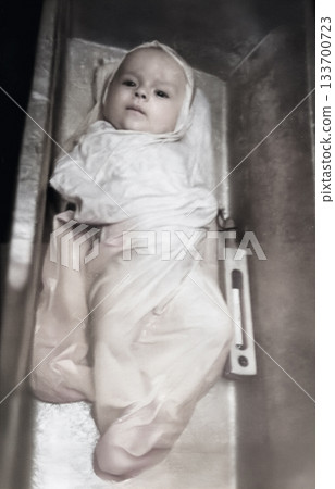 A vintage portrait of a newborn baby boy being bathed in a tub with a thermometer. Retro photo from 1961. A vintage portrait of a newborn baby boy being bathed in a tub with a thermometer. Retro photo from 1961. 133700723